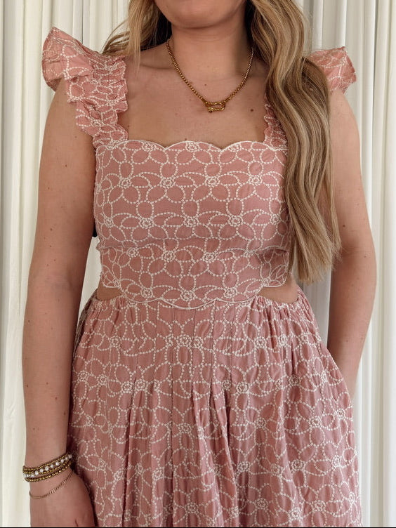 Woman wearing a pink floral dress against a white curtain background