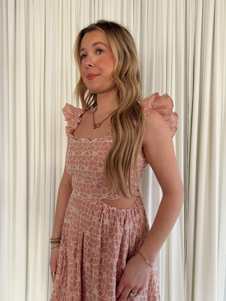 Woman wearing a pink floral dress against a white curtain background