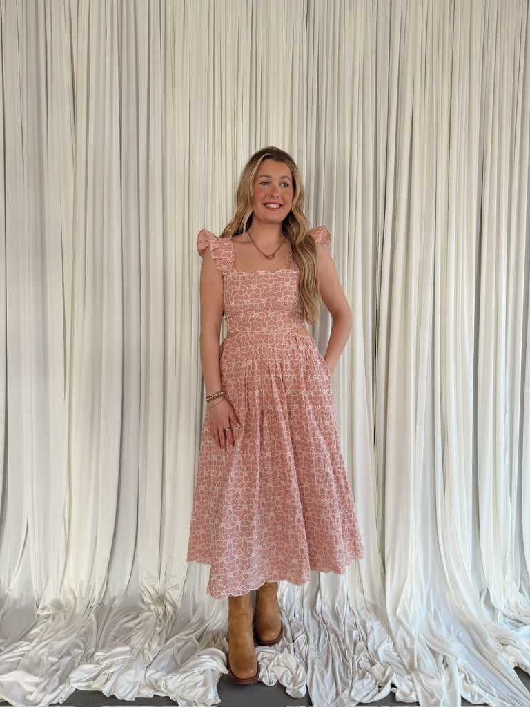 Woman wearing a pink dress standing against a white draped curtain backdrop
