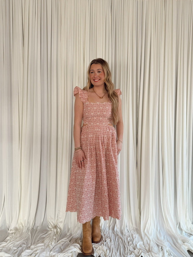 Woman in a pink dress standing in front of a white draped curtain